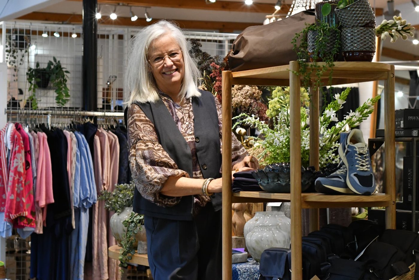 Marianne smiler ved reolen i butikken