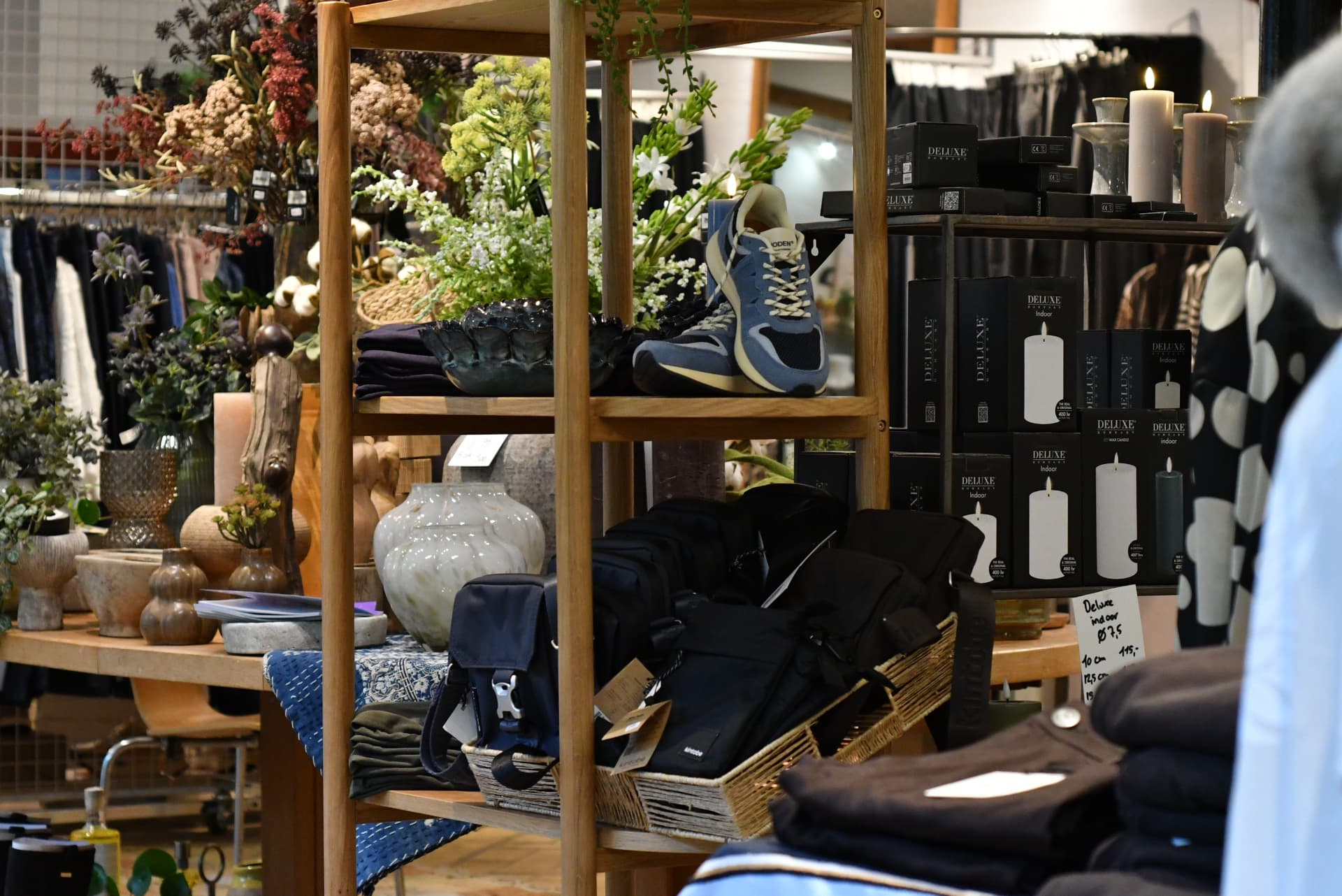 Reol i butikken med blomster, sko, tasker, vaser og lys