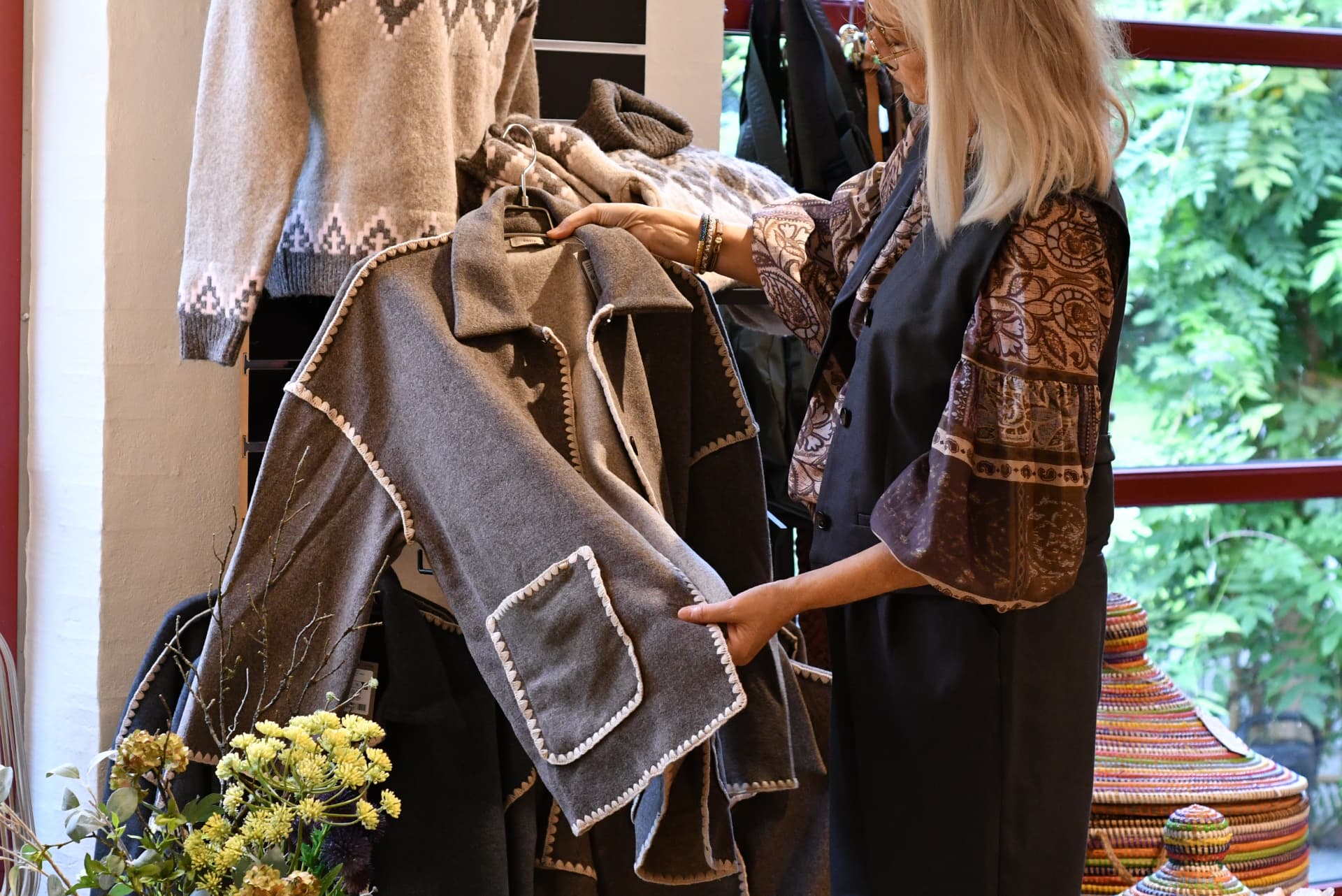 Marianne viser en jakke frem i butikken